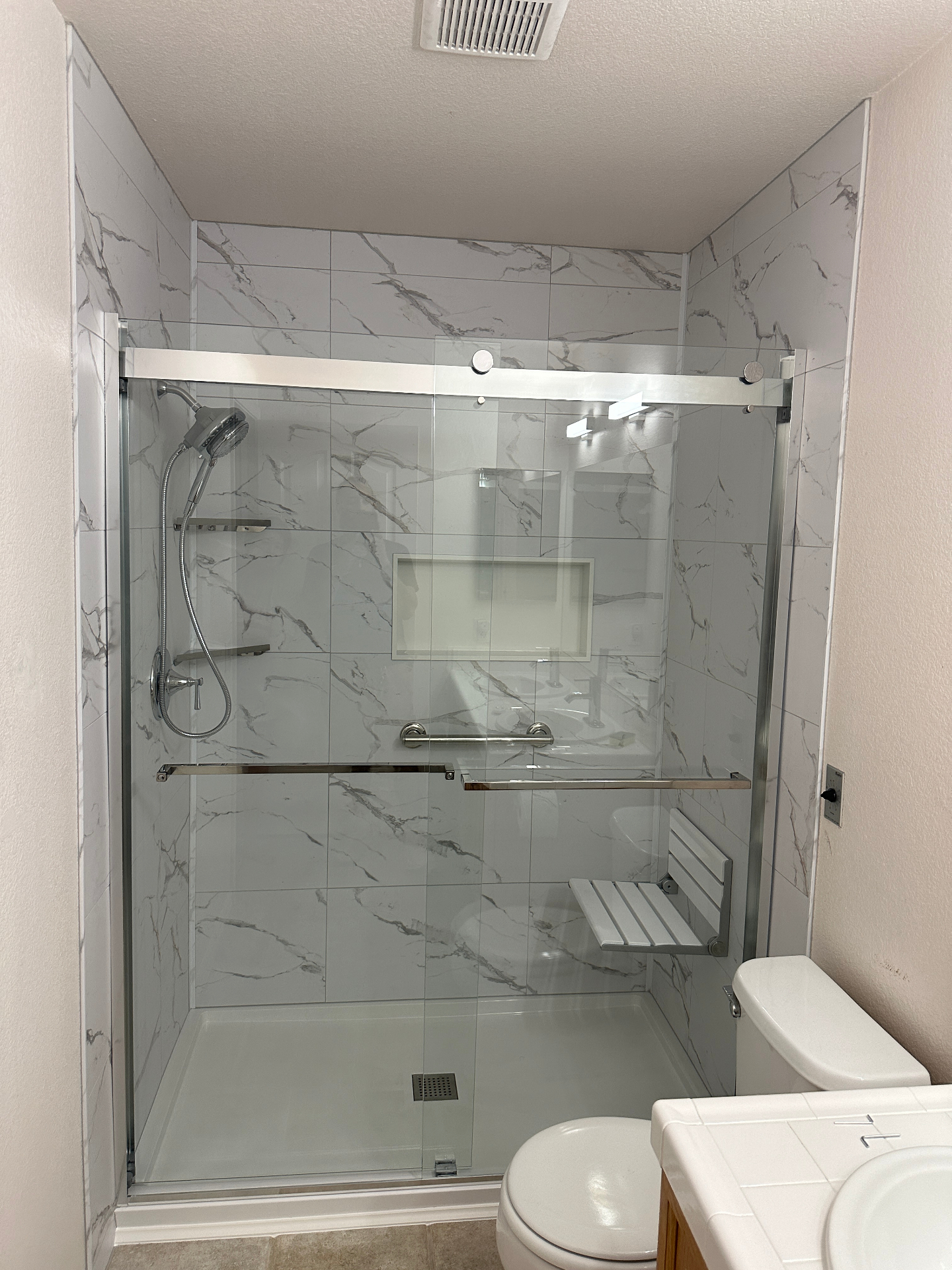 Accessible walk-in shower with grab bars, built-in bench seat, and slip-resistant flooring