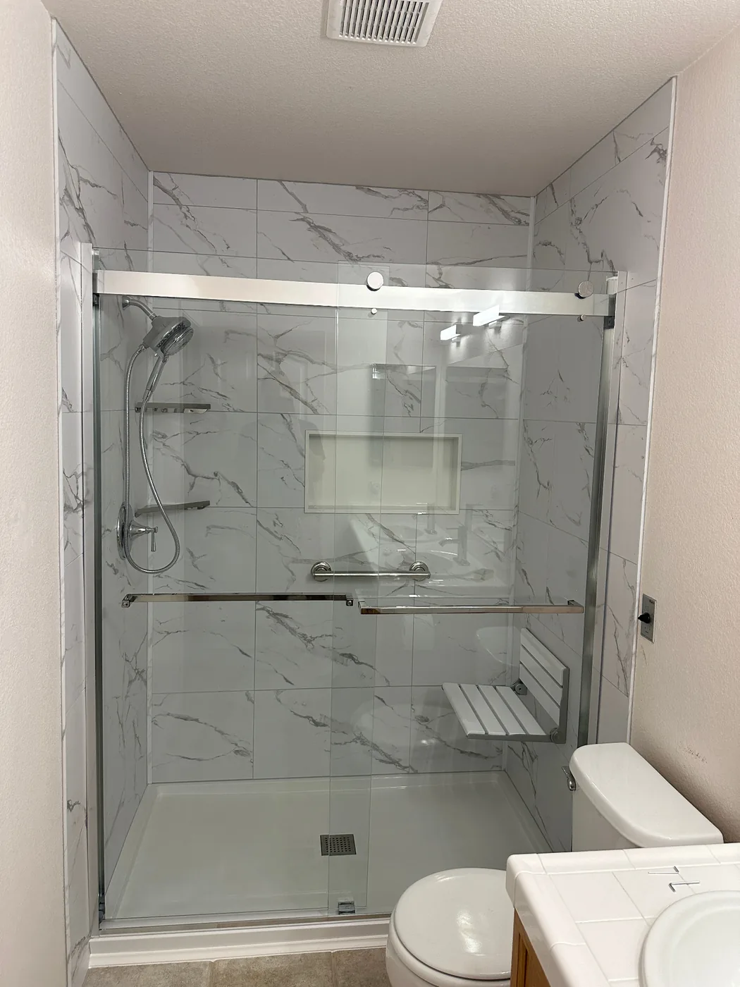 Accessible walk-in shower with grab bars, built-in bench seat, and slip-resistant flooring
